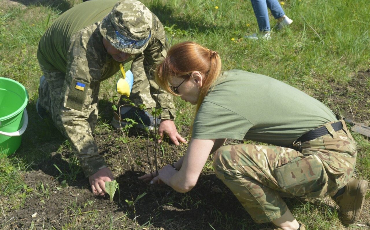 Two people planting wearing army attire.